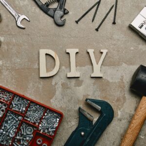 Top view of do it yourself sign and various carpentry tools arranged on old surface background