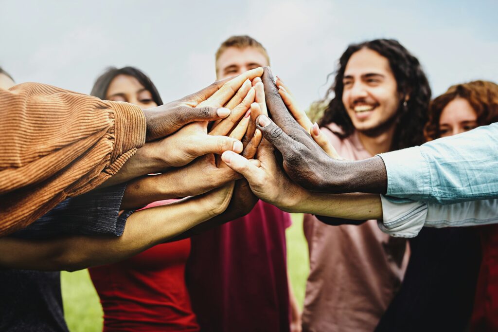 Joyful group of multi-ethnic community of happy people having fun joining hands in the park